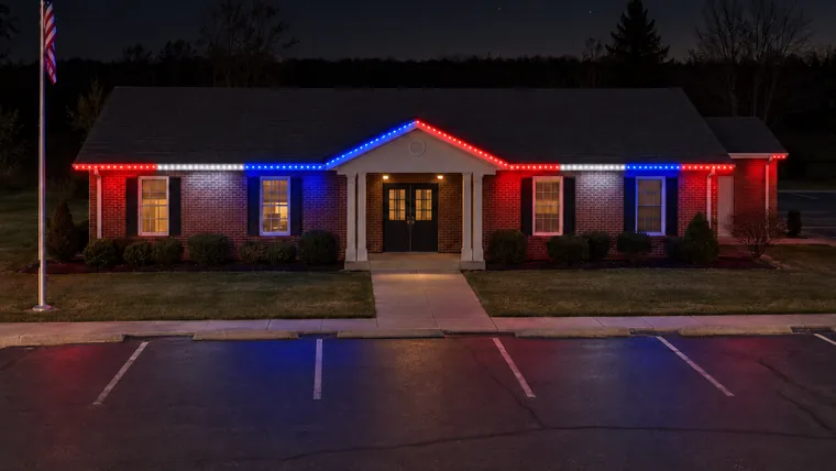A township hall at night with permanent roofline lighting set to fourth of july