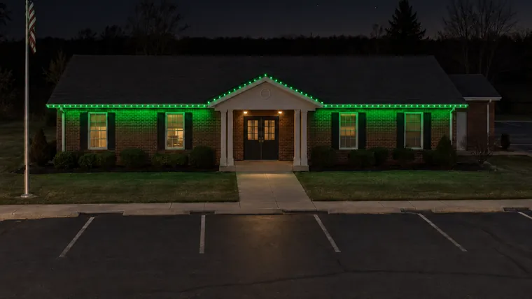 A township hall at night with permanent roofline lighting set to green