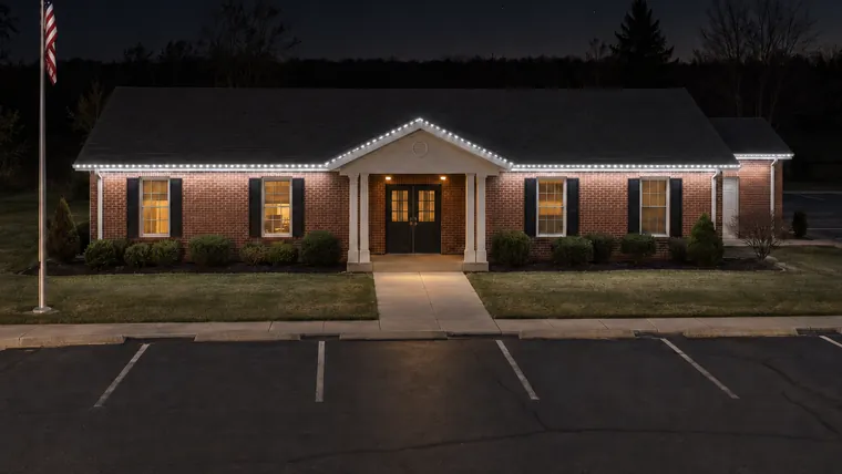 A township hall at night with permanent roofline lighting set to security